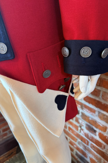 Close-up of a Colonial military uniform with red coat, navy cuffs, and brass buttons