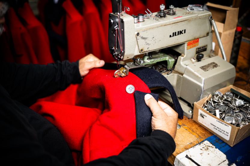 Craftsperson sewing a Colonial military uniform on an industrial sewing machine